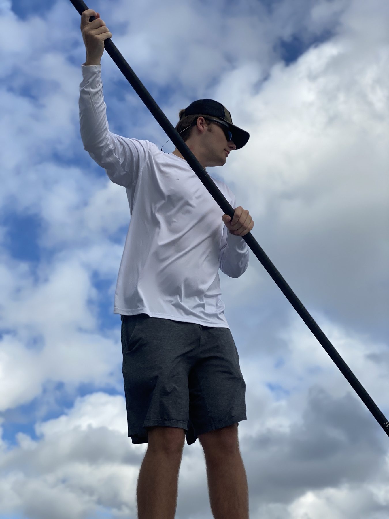 A guide poles a skiff against a backdrop of towering clouds